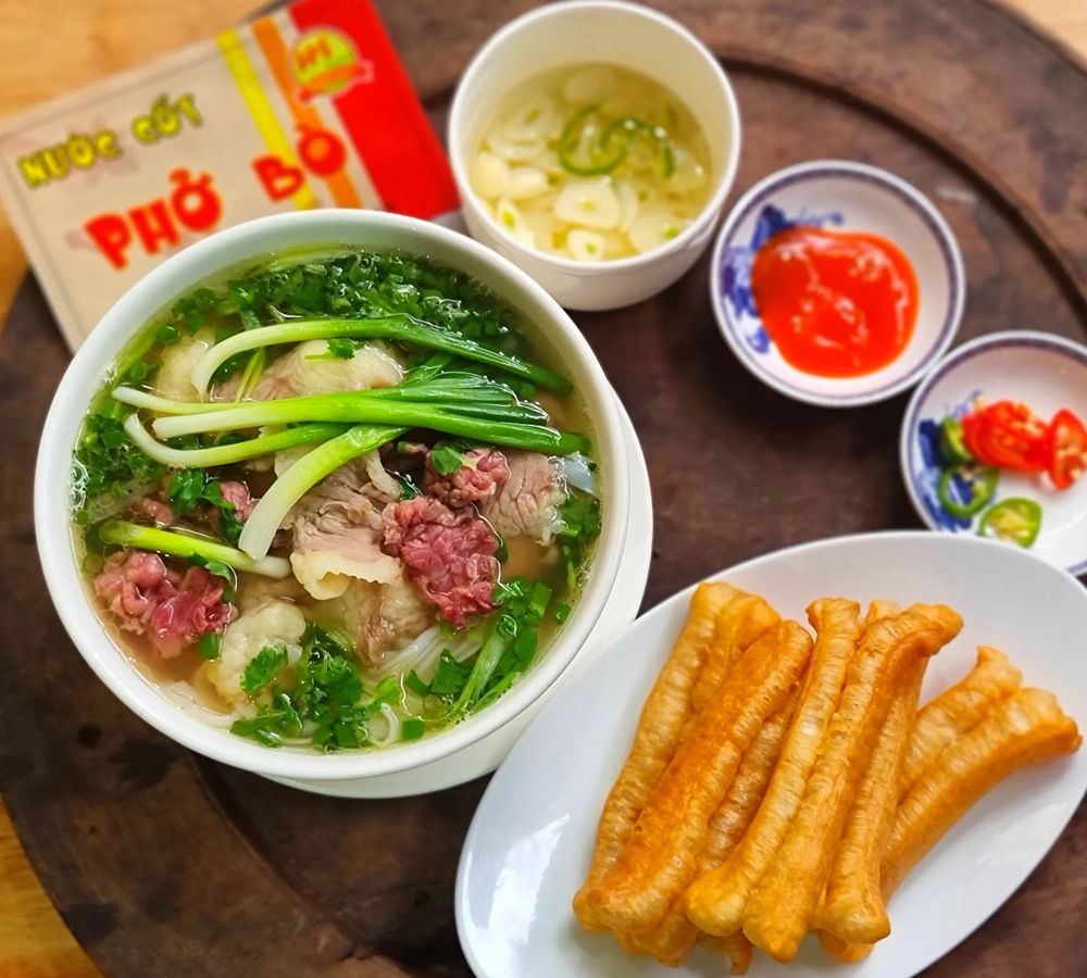 Phở Nam mit Rindfleisch, Kräutern und verschiedenen Beilagen in einer Schale